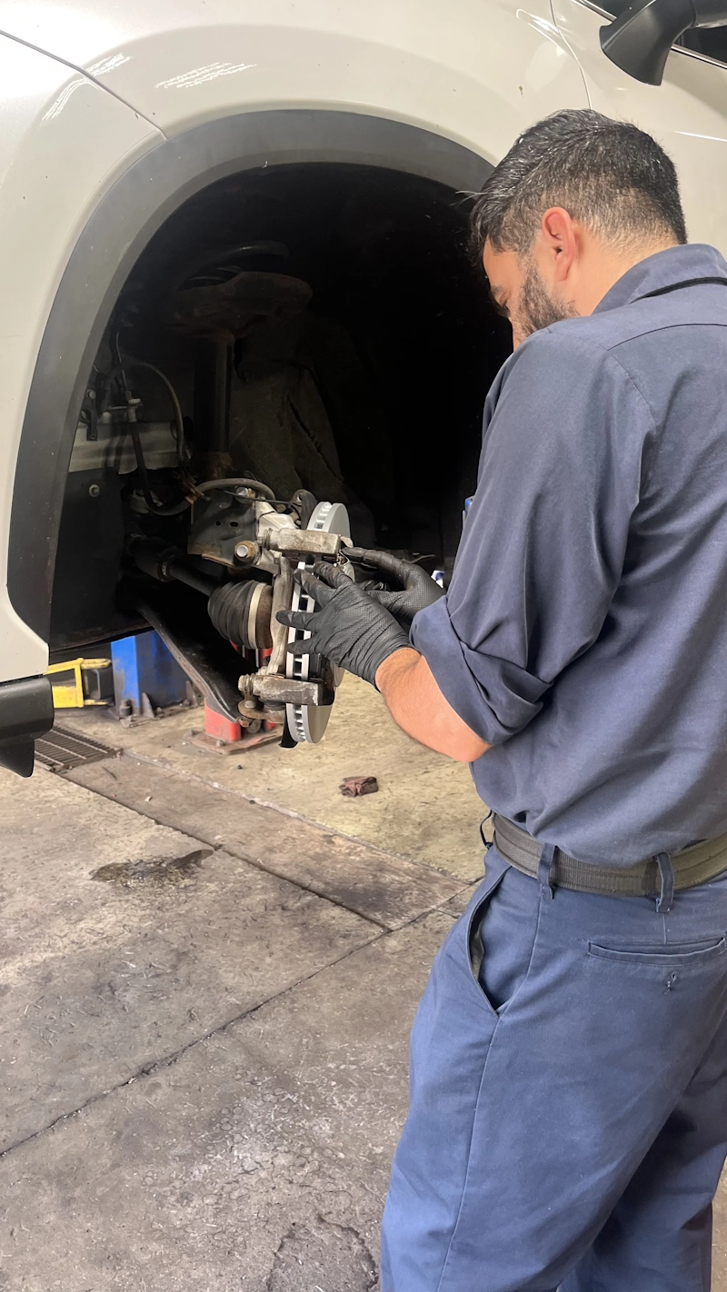 Technician performing a vehicle inspection at Leopard Motors